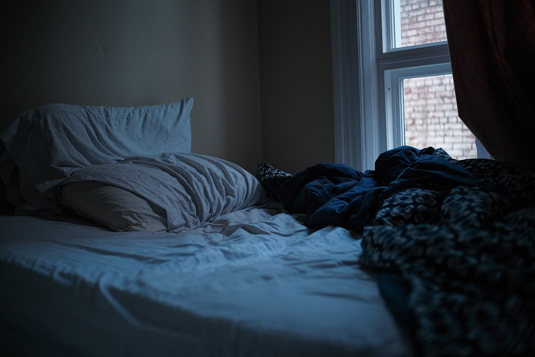 Unmade bed in dark bedroom representing sleepless nights from financial anxiety
