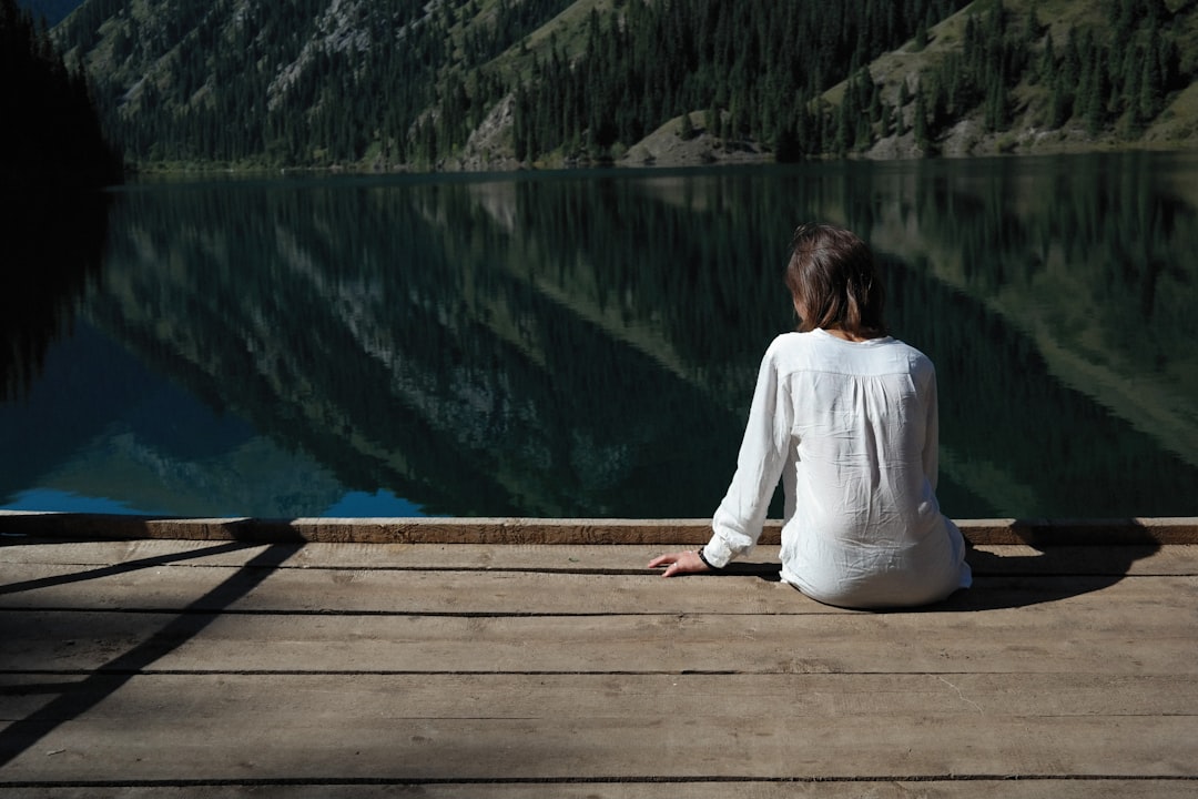Woman sitting calmly by a lake, representing thoughtful decision making