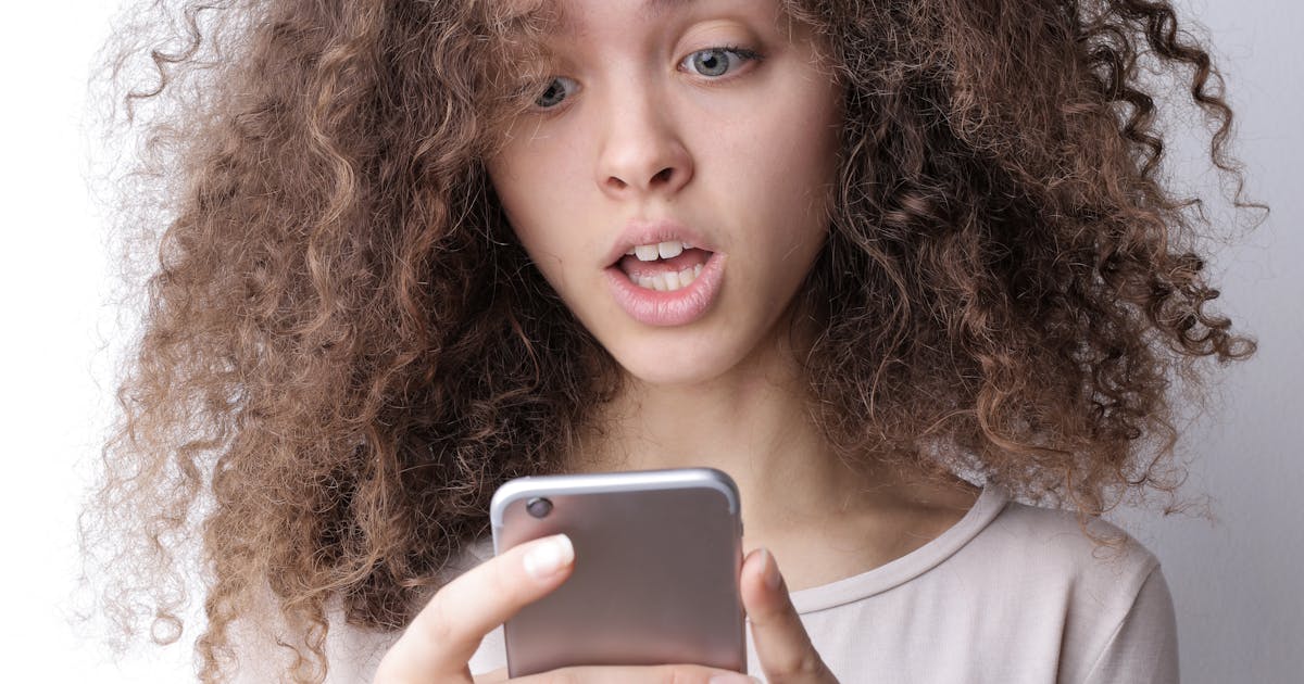 Young woman looking at her phone with a worried expression