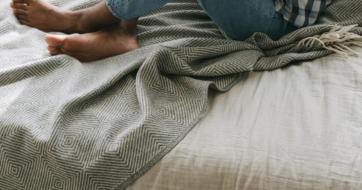 Person sitting in bed using phone with credit card for online shopping