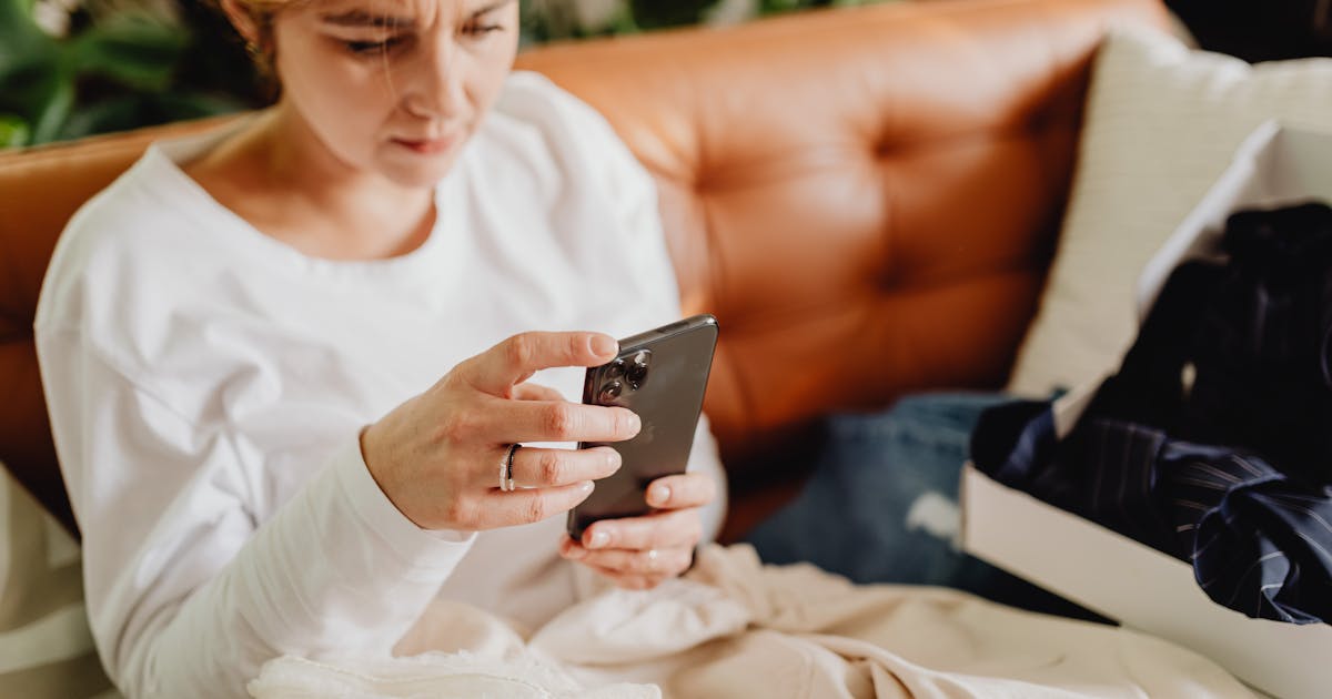 Woman sitting on couch scrolling through phone
